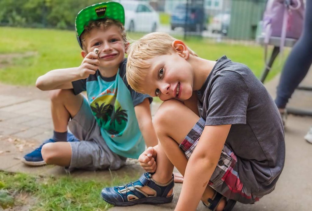 Two boys sitting on the sidewalk playing