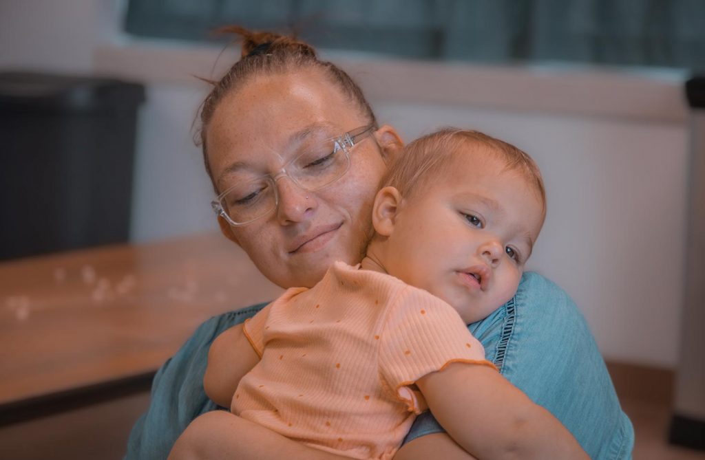 A teacher holding a sleeping infant