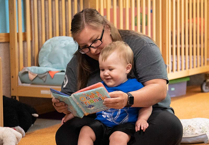A teacher reading to a child in her lap