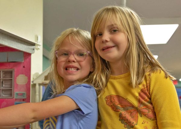 Two school age students playing with a doll house